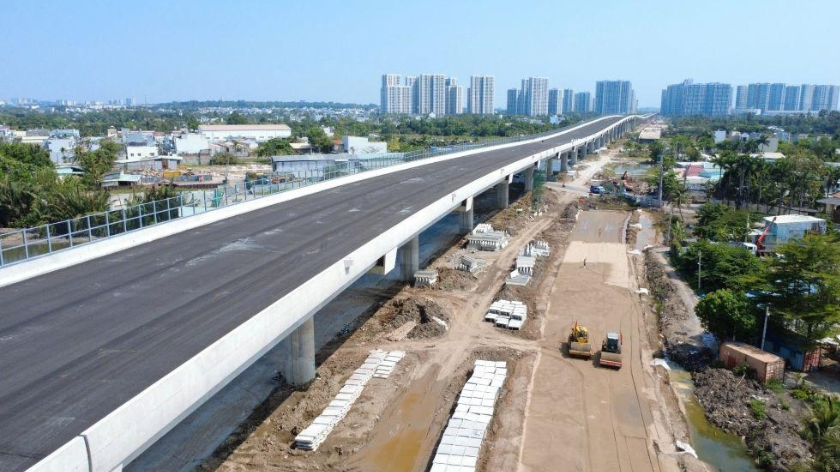 Hình ảnh chụp thực tế đoạn cầu cạn Vành đai 3 với mặt đường đã được thảm nhựa, công trình đang thi công và các khu căn hộ xung quanh. Phù hợp cho phần phân tích tác động của hạ tầng giao thông liên vùng.